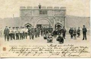 Deutsche Soldaten und Chinesen vor dem Tor des Militärstützpunktes in Tsingtau