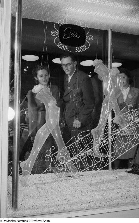 Besucher der Leipziger Herbstmesse 1954 begutachten Damenstrümpfe aus Polyamid-Faser der Marke Esda