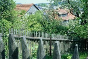 Gartenzaun hinter dem Dorf; abgeschrägte Spitzen an einem Staketenzaun
