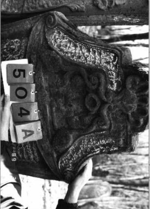 Grabstein 504 (Index: 99752922) Material: Sandstein Zustand: stark verwitt. mit fast völl. Textverlust Maße HxBxT: 117x68x11 cm Beschreibung: Stele, in Voluten auslaufender eingezog. Rundbogenabschl. Symbolik: zwei Trauben, Voluten, Muschel: Grabstein 504A
