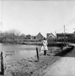 Dorfteich nach Auffüllung mit Wasser: am Ufer Mädchen: rechts Dorfstraße: im Hintergrund Wohn- und Bauernhäuser