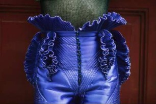 Aufnahme für die Reportagereihe „Außenseiter der Mode“: Studio Fong Leng, Amsterdam : Model in einer lilafarbenen Hose nach einem Entwurf von Fong Leng, vor einer roten Tür