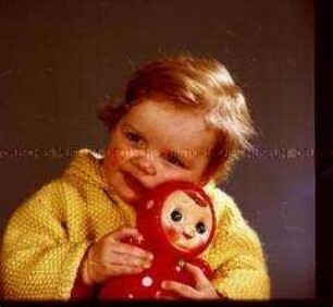 Kleines Mädchen mit Strickjacke und Puppe