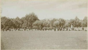 Ulanen in Uniform mit Mütze in Reihe stehend bzw. kniend mit angelegtem Gewehr beim Übungsschiessen im Gelände