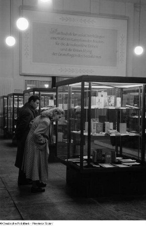 Besucher betrachten die in Vitrinen ausgestellten Exponate bei der 2. Deutschen Buchkunst-Ausstellung