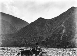Cordillera de Jujuy : Reiter mit Lasttieren in einem Tal. Im Hintergrund Gebirgsansicht
