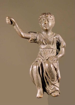 Sitzende Knabenfigur, mit einem geschlitzten, langen Chiton bekleidet, die Rechte erhoben (modern)