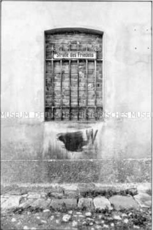 Hauswand mit Straßenschild im zugemauerten Fenster