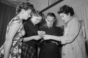 Vier Personen begutachten auf der Leipziger Herbstmesse 1955 Schmuck