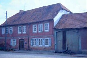 Bauernhof: traufständiges Wohnhaus, Fensterläden im EG, zweiflügelige Haustür, Torfahrt