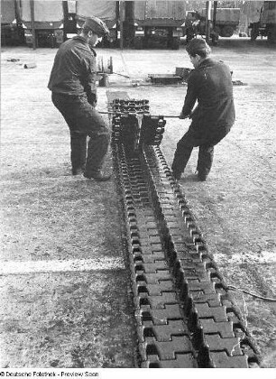 Goldberg (Kreis Lübz). Nationale Volksarmee - Landstreitkräfte. Panzerregiment 8 (PR-8). Freifläche vor Panzerhallen. Soldaten bei Instandsetzungs- bzw. Wartungsarbeiten an Gleisketten für Kampfpanzer T-54