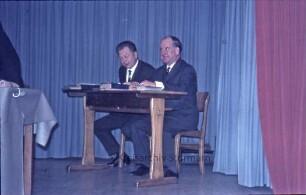 Kreistagssitzung: Kreisberufsschule [Bad Oldesloe]: Grabauer Straße / Ecke Lorentzenstraße: Aula, Bühne: Präsidiumstisch: zwei Schriftführer