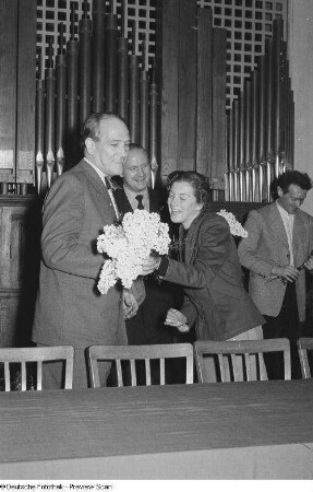 Eine junge Frau überreicht Michael Tschesno-Hell einen Blumenstrauß