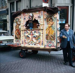 Amsterdam, Drehorgel in der Altstadt : Amsterdam. Drehorgelspieler bittet vor seiner Drehorgel um Gage