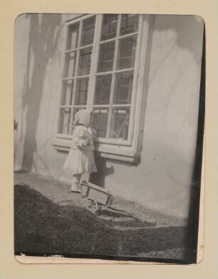 Christiane von Hofmannsthal als Kleinkind im Garten zum Fenster hinein schauend