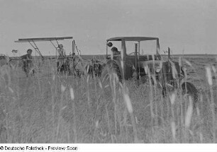Landwirte beim Mähen von Getreide mit Hilfe eines Traktors und einer Mähmaschine