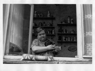 Frau mit einem Zwergkaninchen am Fenster