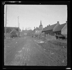 Gavrelle (Dep. Pas-de-Calais, Frankreich): morastige Ortsstraße mit Blick auf eine Kirche