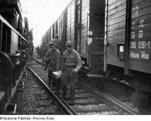 Deutschland . Truppenübungsplatz Klietz. Nationale Volksarmee - Landstreitkräfte. Truppenverlegung per Eisenbahnmarsch. Soldaten zwischen zwei Militärzügen (links Flachwagen mit Militärtechnik, rechts Mannschaftswagen)