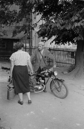 Jahna. Eine Frau und ein Mann mit Motorrad im Gespräch