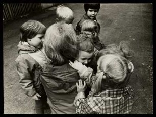 Eine Gruppe von Kindern und eine Frau trösten ein weinendes Kind