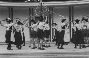 Menschen in Tracht tanzen um einen Maibaum