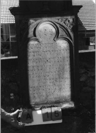 Grabstein 15 (Index: 99797968) Material: Sandstein, weiß Zustand: leicht verwittert Maße HxBxT: 178x60x21 cm Beschreibung: Stele, eingezogener Rundbogenabschluß, getreppter Sockel Symbolik: Levitenkanne, Ranken, Dreipaßbögen: Grabstein 15A