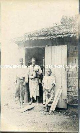 Zwei Männer und ein Junge vor der Küche der Station Molundu
