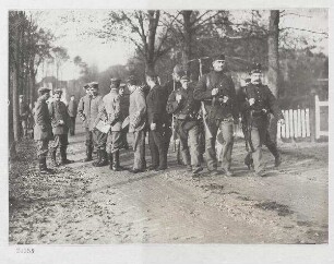 Im holländischen Internierungslager in Bergen (Nordholland). Deutsche Soldaten beim Spaziergang im Lager. Rechts eine abgelöste holländische Wache