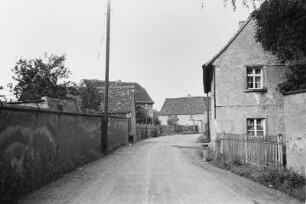 Junge auf einer Straße : Blick entlang einer Straße; links und rechts Mauern und Häuser