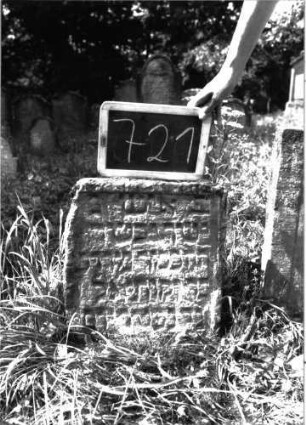 Grabstein 721 (Index: 100104805) Material: Sandstein Zustand: teilweise stark verwittert, eingesunken Maße HxBxT: 47x38x9 cm Beschreibung: hochrechteckige Stele, Schriftfeld eingetieft, Rahmen unregelmäßig gearbeitet: Grabstein 721