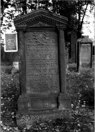 Grabstein 109 (Index: 100111225) Material: Sandstein Zustand: leicht verwittert Maße HxBxT: 150x69x21 cm Beschreibung: ädikulaartige Stele mit Halbsäulen, getreppter Sockel, giebelartiger Abschluß mit Verdachung Symbolik: gekreuzte Zweige, Blüte, Zackenfries: Grabstein 109
