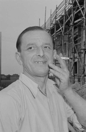 Eine Person vor einer Baustelle beim Rauchen einer Zigarette