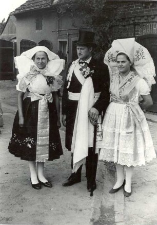 Hochzeitsbitter mit seiner Frau aus Kunersdorf : Kleidung - niedersorbische Tracht. Ort: Kósobuz / Kunersdorf. Der Hochzeitsbitter mit seiner Frau und ein Mädchen in der Kleidung für die Fastnacht und für das Hahnrupfen.