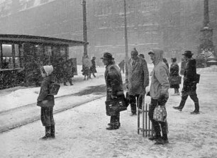 Hamburg-Altstadt. Der Rathausmarkt im Winter. Fahrgäste stehen an der Haltestelle und warten auf die Straßenbahn