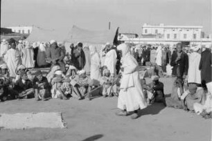 Reisefotos Marokko. Straßenkünstler mit Zuschauern während einer Vorführung. Im Hintergrund Gebäude "Minoterie algerienne" (vielleicht in Casablanca)