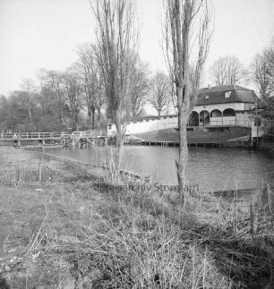 Trave: vorn Baumreihe am Ufer: hinten rechts alte Badeanstalt: hinten links Holzbrücke: dahinter Bäume des Bürgerparks
