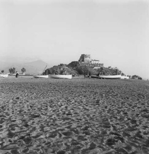 Kalabrien, Scalea, Blick über den Strand mit Booten auf einen Felsen mit der Ruine des Küstenturms Torre Talao