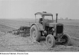 Bauer mit Traktor beim Pflügen eines Feldes