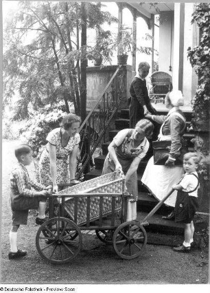Villa. Treppenaufgang zur Gartenterrasse. Zwei Frauen mit zwei kleinen Jungen, einen Ziehwagen abladend : Villa. Treppenaufgang zur Gartenterrasse. Zwei Frauen mit zwei kleinen Jungen, einen Ziehwagen abladend; ältere Dame eine Krankenschwester auf der Treppe verabschiedend
