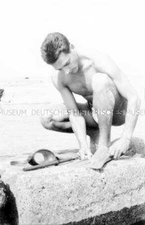 Urlauber am Strand von Zingst beim Anlegen seiner Schwimmflossen