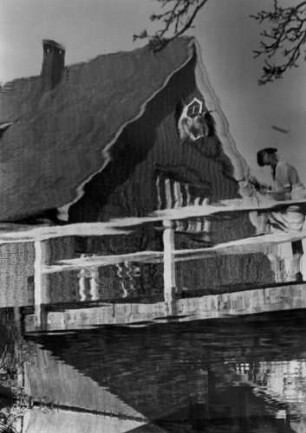 Der Giebel eines Bauernhauses spiegelt sich im Wasser