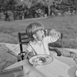 Junge isst auf einer Terrasse