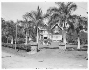 Honolulu (Hawaii). Anwesen mit Wohnhaus und Garten. Ansicht mit Heckeneinfriedung und Palmen