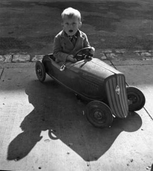 Kinderbilder. Kleiner Junge in einem Spielzeugauto in Bayreuth