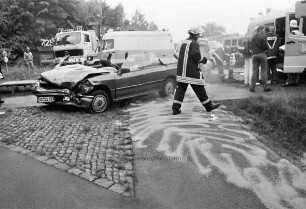 Ostring: Verkehrsunfall mit zwei Pkws: verunglückter Pkw mit eingedrückter Front und abgetrenntem Dach: hinten Rettungs-, Feuerwehr- und Polizeifahrzeuge: dazwischen Rettungskräfte: vorn abgestreute Straße: 11. Juni 1999