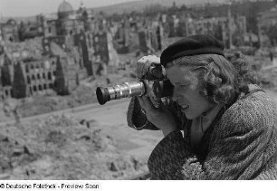 Renate Rössing beim Fotografieren vor Gebäudetrümmern