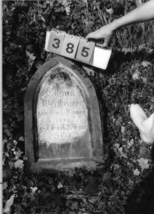 Grabstein 385 (Index: 99792086) Material: Sandstein Zustand: leicht verwittert, Stele liegend Maße HxBxT: 65x38x16 cm Beschreibung: Stele, Spitzbogenabschluß, Schriftfeld eingetieft Besonderheit: Kindergrab: Grabstein 385