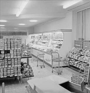 Peters Delikatessen: Mühlenstraße, Ecke Hindenburgstraße: Feinkostgeschäft: Innenaufnahme: Blick in Verkaufsraum: Regale mit Waren, Kühltheke, Einkaufswagen, Einkaufskörbe: vorne Kasse