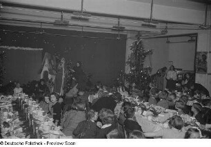 Blick auf an Tischen sitzende Kinder und die Bühne mit Weihnachtsmann
